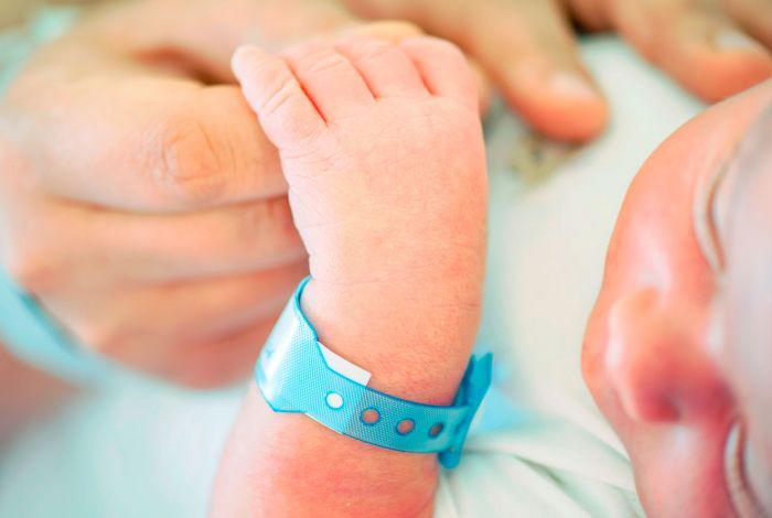 Newborn baby holding parents hands